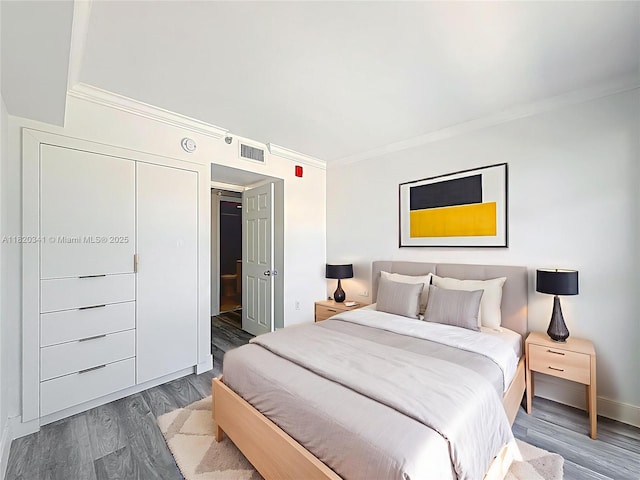 bedroom featuring ornamental molding and wood finished floors