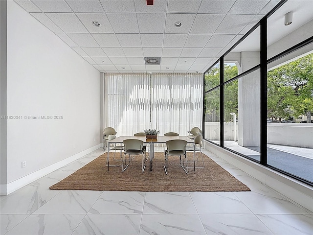 dining area with marble look tile flooring and baseboards