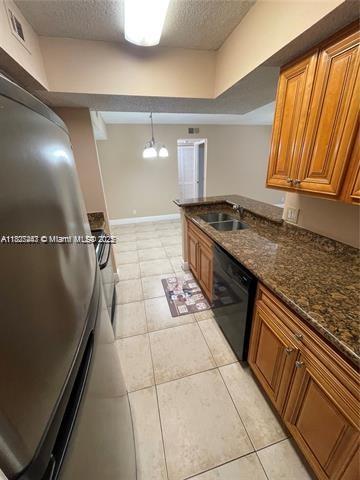 5780 Rock Island Rd Unit 354, Tamarac, FL 33319 - kitchen with black dishwasher, a textured ceiling, brown cabinetry, light tile patterned flooring, and dark stone countertops