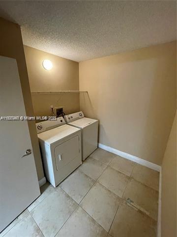 5780 Rock Island Rd Unit 354, Tamarac, FL 33319 - laundry area featuring washing machine and dryer, a textured ceiling, and light tile patterned flooring