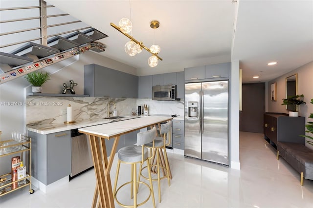 41 SE 5th St Unit 2306, Miami, FL 33131 - kitchen featuring appliances with stainless steel finishes, gray cabinets, backsplash, light countertops, and a breakfast bar area