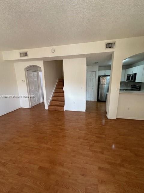 11479 NW 60th Ter Unit 372, Doral, FL 33178 - unfurnished living room featuring a textured ceiling, wood finished floors, stairs, and arched walkways