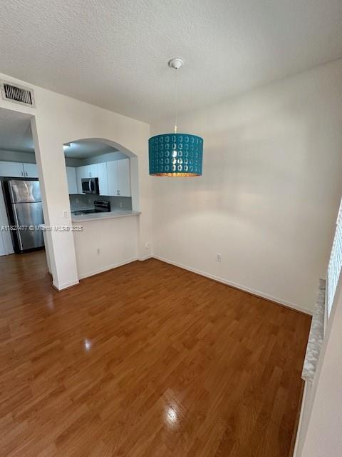11479 NW 60th Ter Unit 372, Doral, FL 33178 - unfurnished dining area with arched walkways, dark wood finished floors, and a textured ceiling