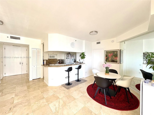 808 Brickell Key Dr Unit 1103, Miami, FL 33131 - kitchen featuring white microwave, a peninsula, and a kitchen breakfast bar
