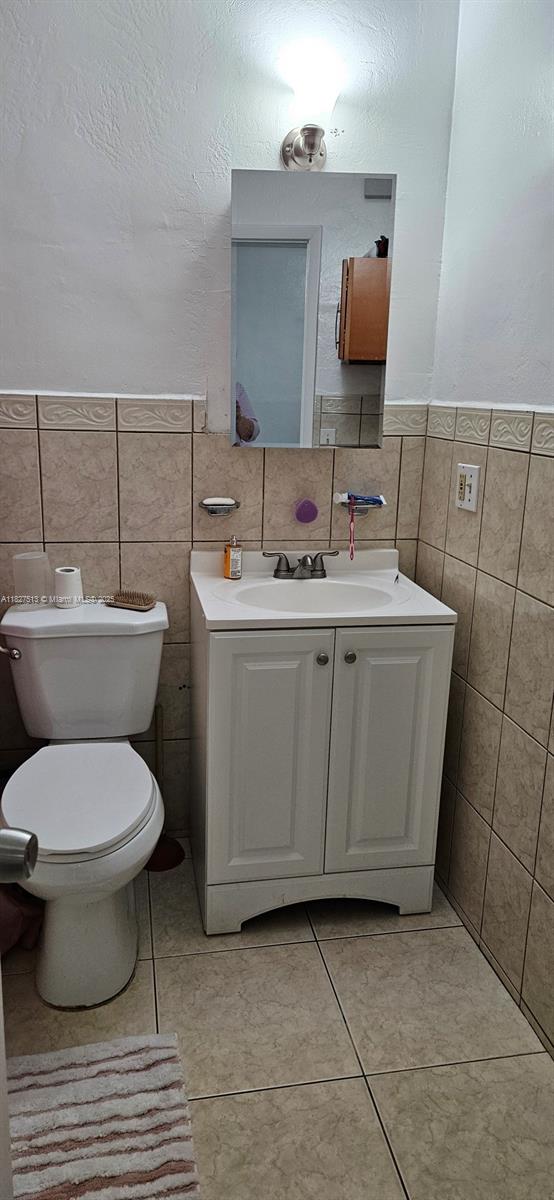 1498 NE 180th St, North Miami Beach, FL 33162 - bathroom featuring tile walls, vanity, tile patterned floors, and a wainscoted wall