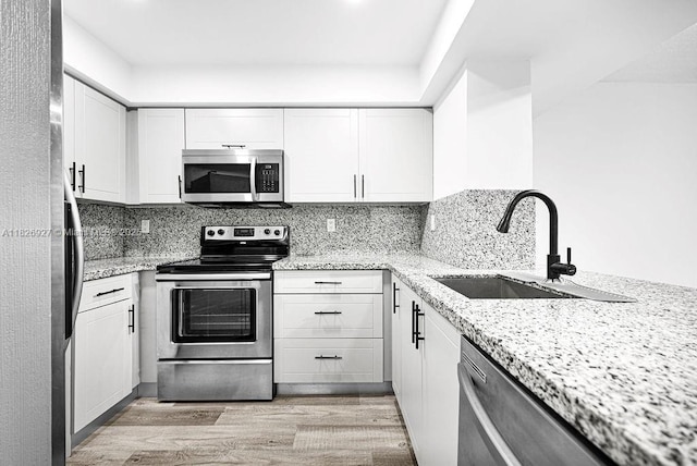 8365 SW 152nd Ave Unit C-201, Miami, FL 33193 - kitchen featuring stainless steel appliances, light wood-style floors, white cabinetry, and backsplash