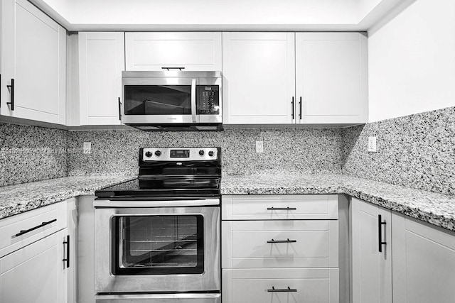 8365 SW 152nd Ave Unit C-201, Miami, FL 33193 - kitchen with stainless steel appliances, white cabinetry, backsplash, and light stone counters