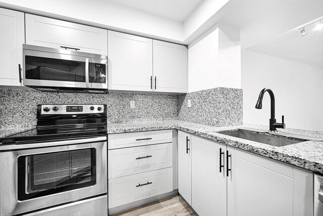 8365 SW 152nd Ave Unit C-201, Miami, FL 33193 - kitchen featuring appliances with stainless steel finishes, white cabinets, light stone counters, and tasteful backsplash