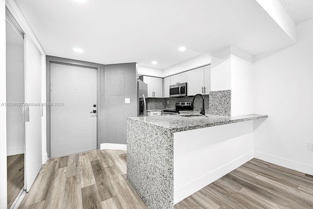 8365 SW 152nd Ave Unit C-201, Miami, FL 33193 - kitchen with stainless steel appliances, light wood finished floors, a peninsula, light stone countertops, and decorative backsplash