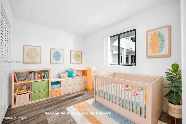 8365 SW 152nd Ave Unit C-201, Miami, FL 33193 - bedroom with wood finished floors, a crib, and a textured ceiling