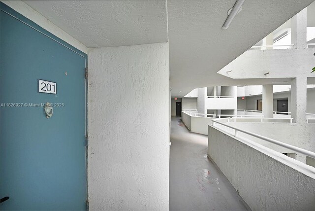 8365 SW 152nd Ave Unit C-201, Miami, FL 33193 - corridor featuring a textured wall, a textured ceiling, and concrete floors