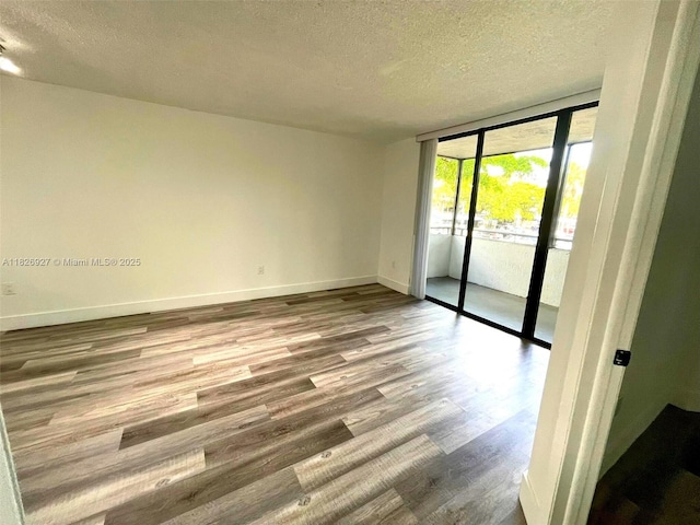 8365 SW 152nd Ave Unit C-201, Miami, FL 33193 - spare room featuring a textured ceiling, expansive windows, and wood finished floors