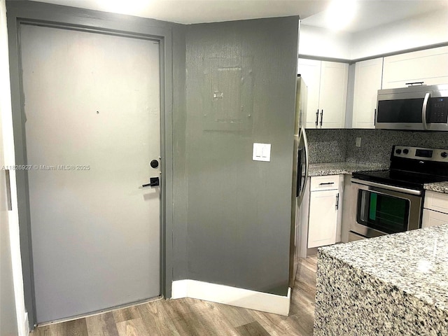 8365 SW 152nd Ave Unit C-201, Miami, FL 33193 - kitchen featuring stainless steel appliances, wood finished floors, white cabinets, and light stone counters