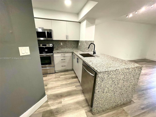 8365 SW 152nd Ave Unit C-201, Miami, FL 33193 - kitchen with stainless steel appliances, light wood finished floors, light stone countertops, a peninsula, and white cabinetry