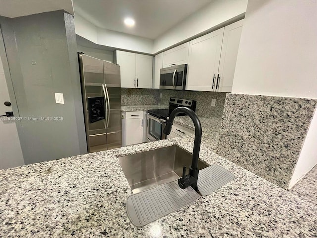 8365 SW 152nd Ave Unit C-201, Miami, FL 33193 - kitchen featuring stainless steel appliances, light stone countertops, white cabinets, and decorative backsplash
