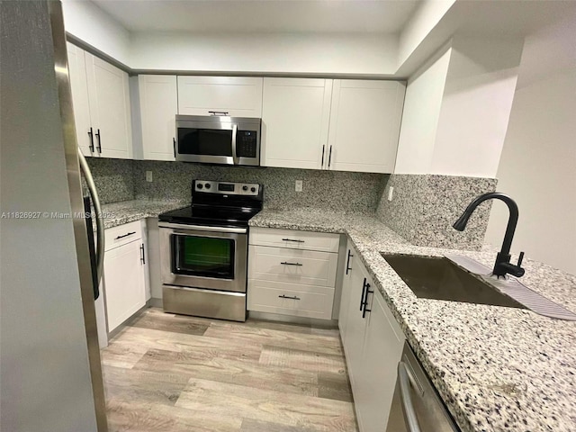 8365 SW 152nd Ave Unit C-201, Miami, FL 33193 - kitchen featuring appliances with stainless steel finishes, light wood-type flooring, white cabinetry, and light stone countertops