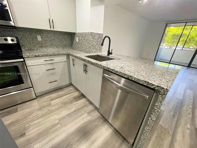 8365 SW 152nd Ave Unit C-201, Miami, FL 33193 - kitchen with appliances with stainless steel finishes, white cabinetry, light wood finished floors, tasteful backsplash, and light stone counters
