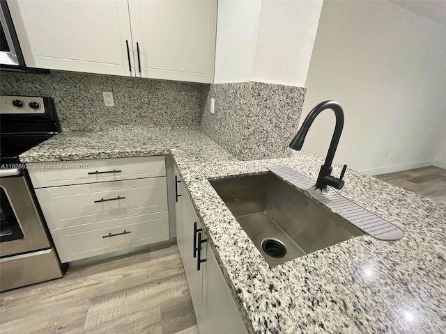 8365 SW 152nd Ave Unit C-201, Miami, FL 33193 - kitchen with stainless steel appliances, light stone countertops, white cabinets, light wood-style flooring, and tasteful backsplash
