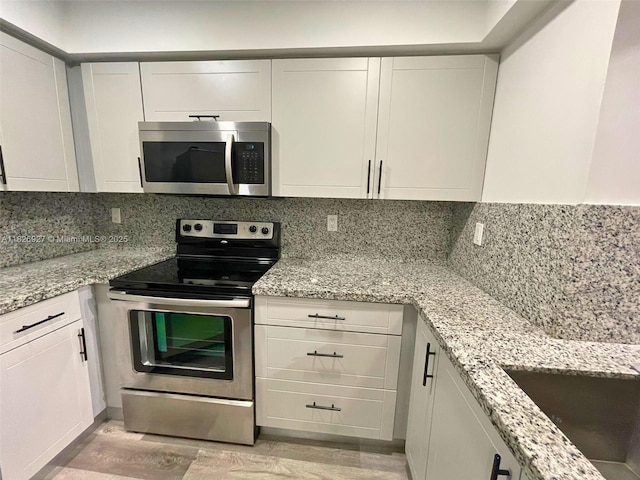 8365 SW 152nd Ave Unit C-201, Miami, FL 33193 - kitchen featuring appliances with stainless steel finishes, white cabinetry, light wood-style floors, and decorative backsplash