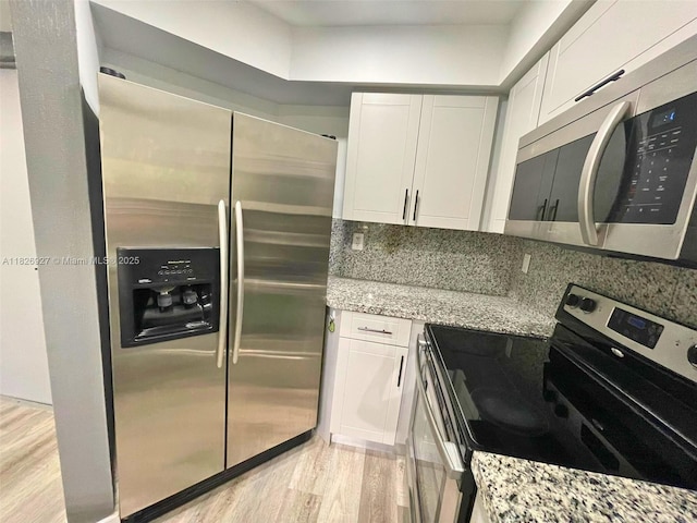 8365 SW 152nd Ave Unit C-201, Miami, FL 33193 - kitchen with appliances with stainless steel finishes, light stone counters, white cabinets, light wood-style flooring, and decorative backsplash