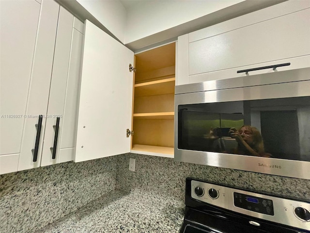8365 SW 152nd Ave Unit C-201, Miami, FL 33193 - kitchen with stainless steel microwave, oven, decorative backsplash, and white cabinets