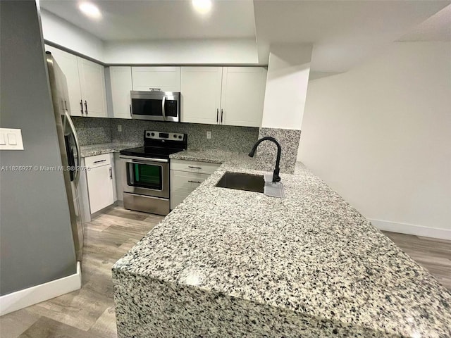 8365 SW 152nd Ave Unit C-201, Miami, FL 33193 - kitchen with stainless steel appliances, light stone countertops, light wood-style floors, backsplash, and white cabinetry