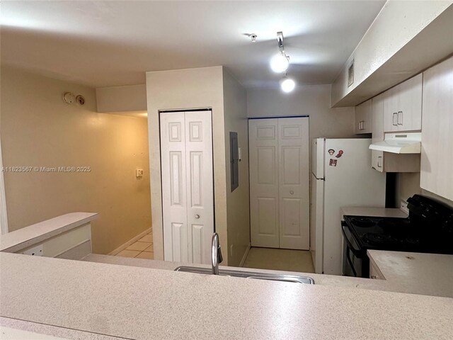 11185 SW 6th St Unit 303, Pembroke Pines, FL 33025 - kitchen featuring electric range, under cabinet range hood, light countertops, white cabinetry, and freestanding refrigerator