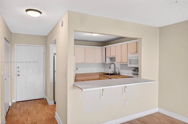 16851 NE 23rd Ave Unit A619, North Miami Beach, FL 33160 - kitchen featuring white microwave, light wood-style floors, light countertops, a textured ceiling, and a breakfast bar area