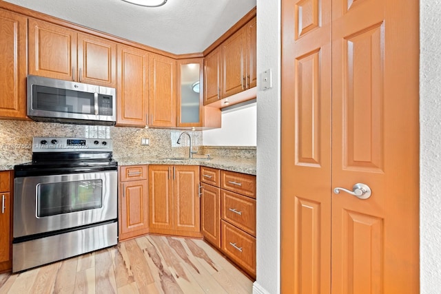 20155 E Oakmont Cir, Hialeah, FL 33015 - kitchen with appliances with stainless steel finishes, light wood-style flooring, light stone counters, tasteful backsplash, and glass insert cabinets