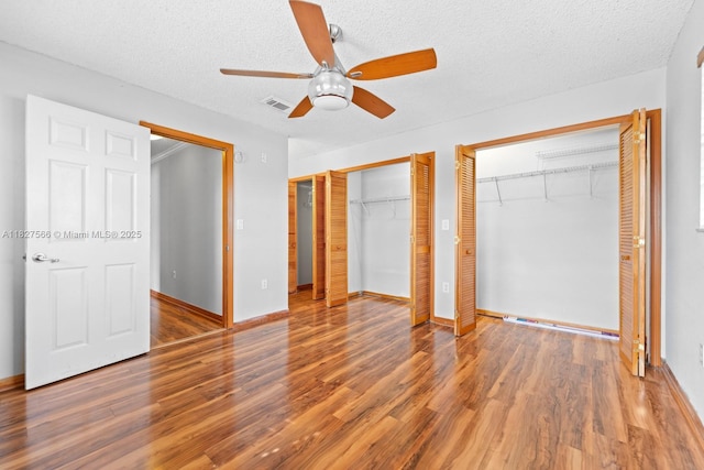 20155 E Oakmont Cir, Hialeah, FL 33015 - unfurnished bedroom with two closets, wood finished floors, a textured ceiling, and ceiling fan