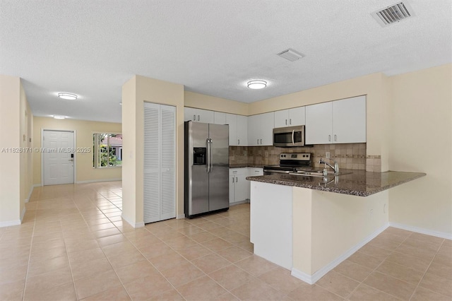 1784 SW 110th Ter, Davie, FL 33324 - kitchen with stainless steel appliances, a peninsula, tasteful backsplash, white cabinets, and dark stone counters