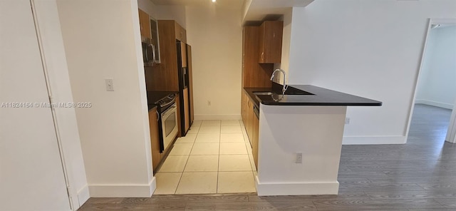 2775 NE 187th St Unit 424, Aventura, FL 33180 - kitchen featuring dark countertops, range, stainless steel microwave, and light wood-style floors