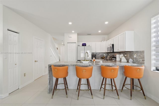9349 W 33rd Way, Hialeah, FL 33018 - kitchen with stainless steel microwave, freestanding refrigerator, stove, light stone countertops, and a peninsula