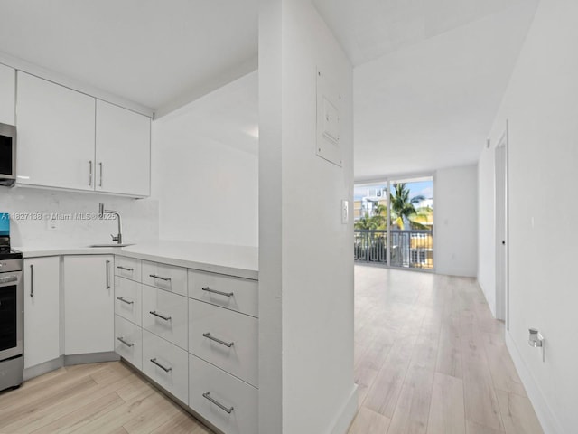 401 Ocean Dr Unit 403, Miami Beach, FL 33139 - kitchen featuring light countertops, white cabinets, light wood-style floors, backsplash, and appliances with stainless steel finishes