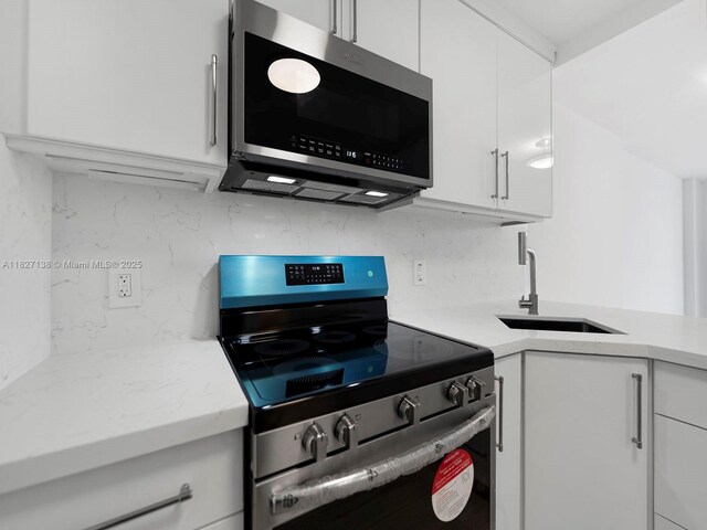 401 Ocean Dr Unit 403, Miami Beach, FL 33139 - kitchen with stainless steel appliances, tasteful backsplash, and white cabinetry