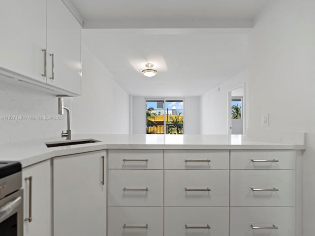 401 Ocean Dr Unit 403, Miami Beach, FL 33139 - kitchen featuring light countertops, white cabinets, a peninsula, and stove