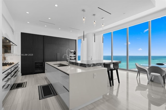 17901 Collins Ave Unit 1607, Sunny Isles Beach, FL 33160 - kitchen with modern cabinets, dark cabinets, a kitchen island with sink, range hood, and a water view