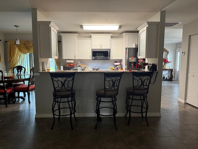 1046 Bayberry Loop, Clewiston, FL 33440 - kitchen with appliances with stainless steel finishes, a peninsula, tasteful backsplash, and a kitchen breakfast bar