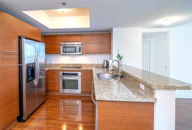 2641 N Flamingo Rd Unit 1603N, Sunrise, FL 33323 - kitchen with appliances with stainless steel finishes, brown cabinets, a peninsula, dark wood-style flooring, and light stone countertops