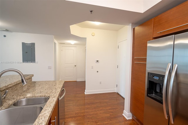 2641 N Flamingo Rd Unit 1603N, Sunrise, FL 33323 - kitchen with stainless steel appliances, brown cabinetry, electric panel, dark wood-style flooring, and light stone countertops