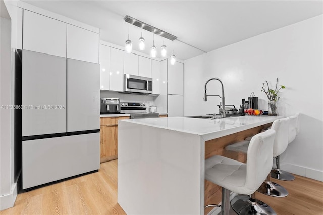 806 SW 119th Way, Davie, FL 33325 - kitchen featuring appliances with stainless steel finishes, light wood-type flooring, a kitchen breakfast bar, and modern cabinets