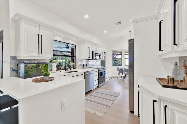 8525 NW 49th Dr, Coral Springs, FL 33067 - kitchen with appliances with stainless steel finishes, light wood-type flooring, light countertops, white cabinetry, and lofted ceiling