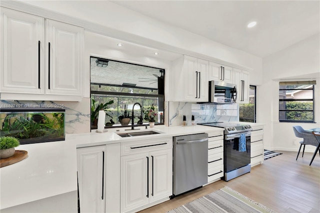 8525 NW 49th Dr, Coral Springs, FL 33067 - kitchen with stainless steel appliances, backsplash, light countertops, white cabinetry, and light wood finished floors