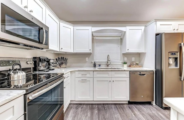 220 Kite Ave, Sebring, FL 33870 - kitchen with stainless steel appliances, light wood-style floors, white cabinets, and light stone counters