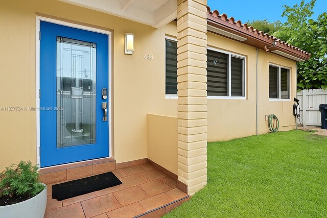 634 82nd St, Miami Beach, FL 33141 - property entrance with stucco siding, a lawn, and a tiled roof