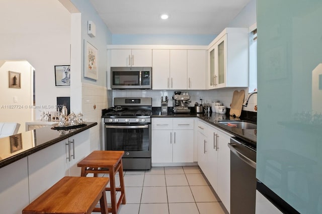 634 82nd St, Miami Beach, FL 33141 - kitchen featuring appliances with stainless steel finishes, arched walkways, decorative backsplash, and white cabinets