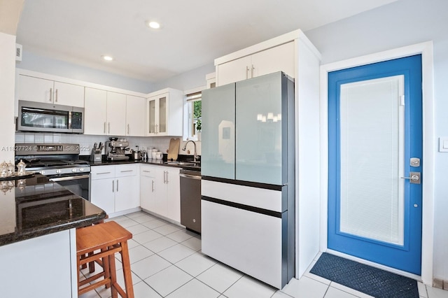 634 82nd St, Miami Beach, FL 33141 - kitchen featuring stainless steel appliances, white cabinetry, dark stone counters, light tile patterned floors, and recessed lighting