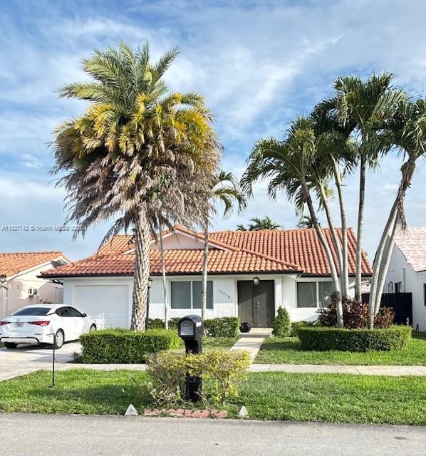 13736 SW 12th St, Miami, FL 33184 - view of front of property with an attached garage, a tiled roof, stucco siding, and driveway