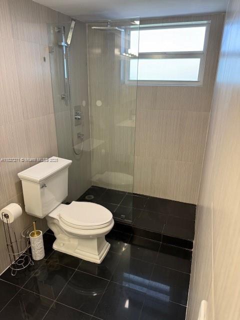 947 Lenox Ave Unit 502, Miami Beach, FL 33139 - bathroom featuring a walk in shower, tile patterned floors, and tile walls