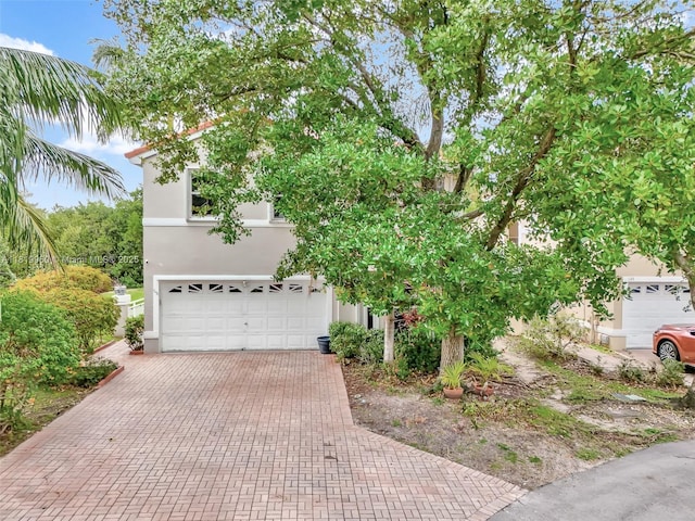 1151 W Lake St, Hollywood, FL 33019 - obstructed view of property featuring stucco siding, a garage, and decorative driveway